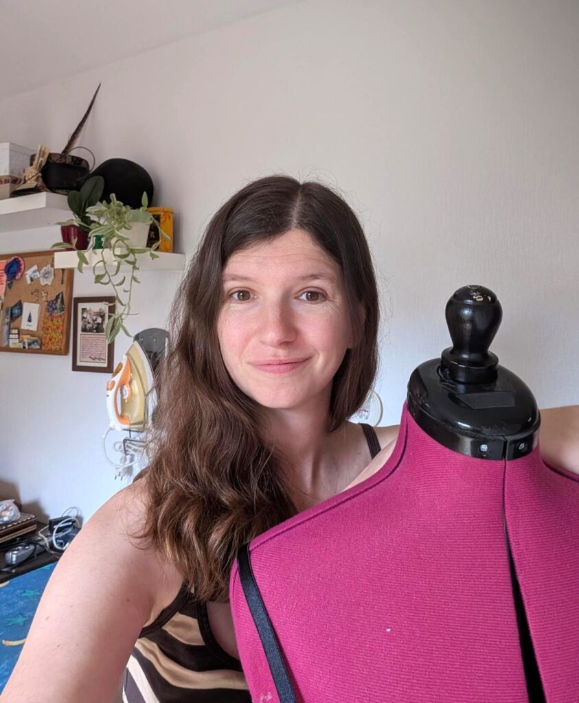 Photo au format portrait de la créatrice, accoudée à son mannequin de couture